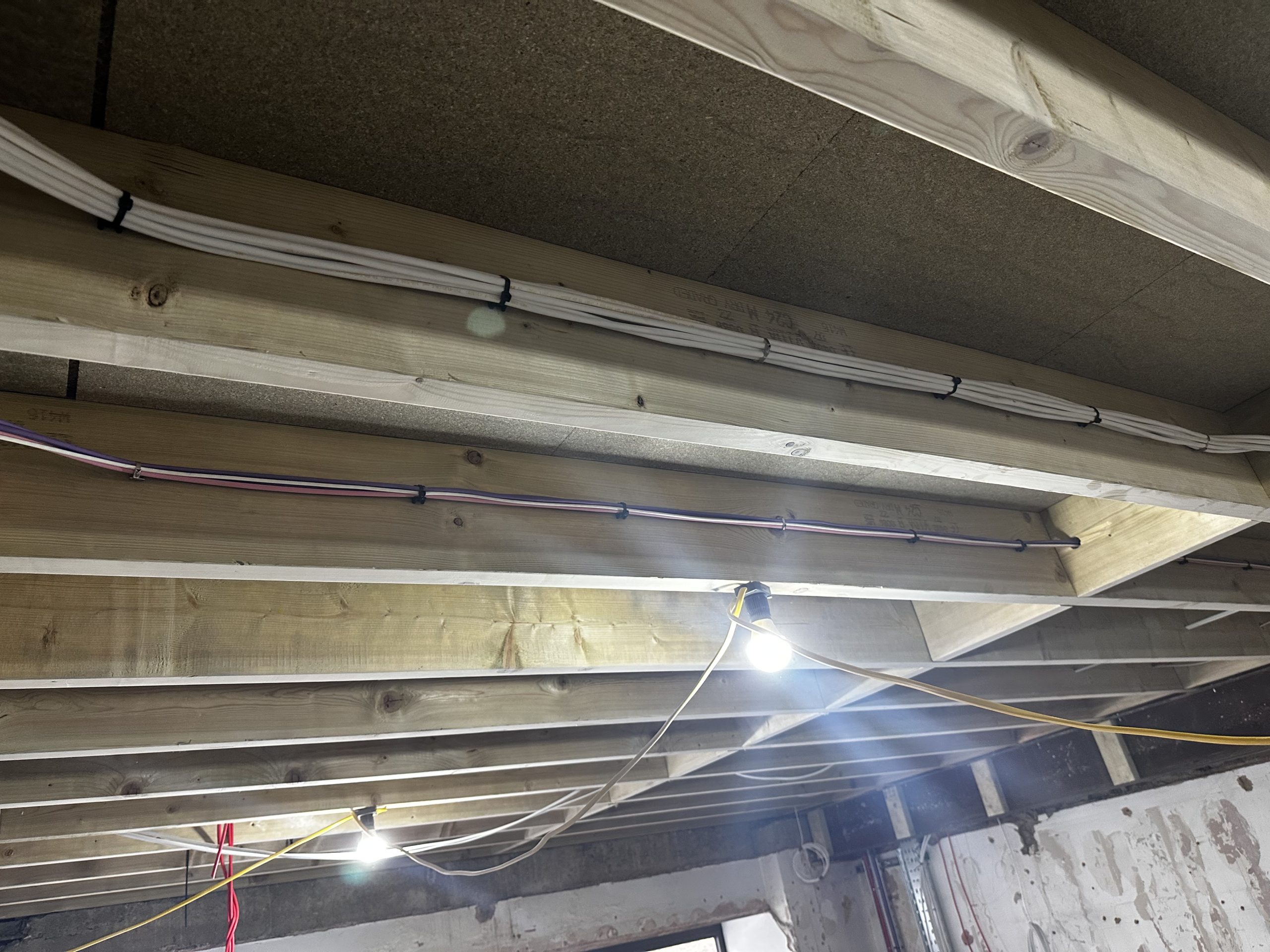 New electrical installation cabling clipped along timber joists during first-fix works.