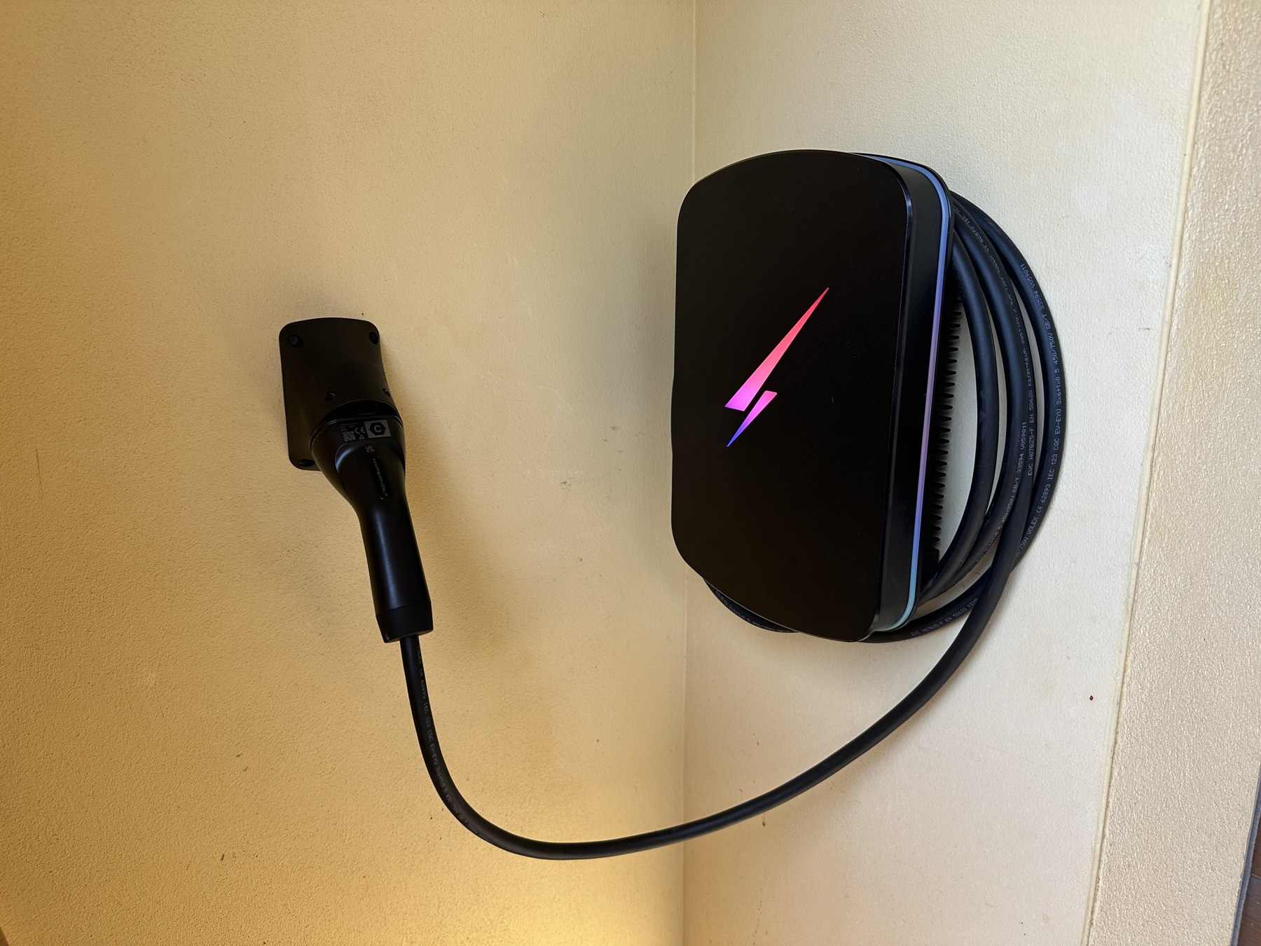Black Hypervolt EV charger and cable installed on a cream wall
