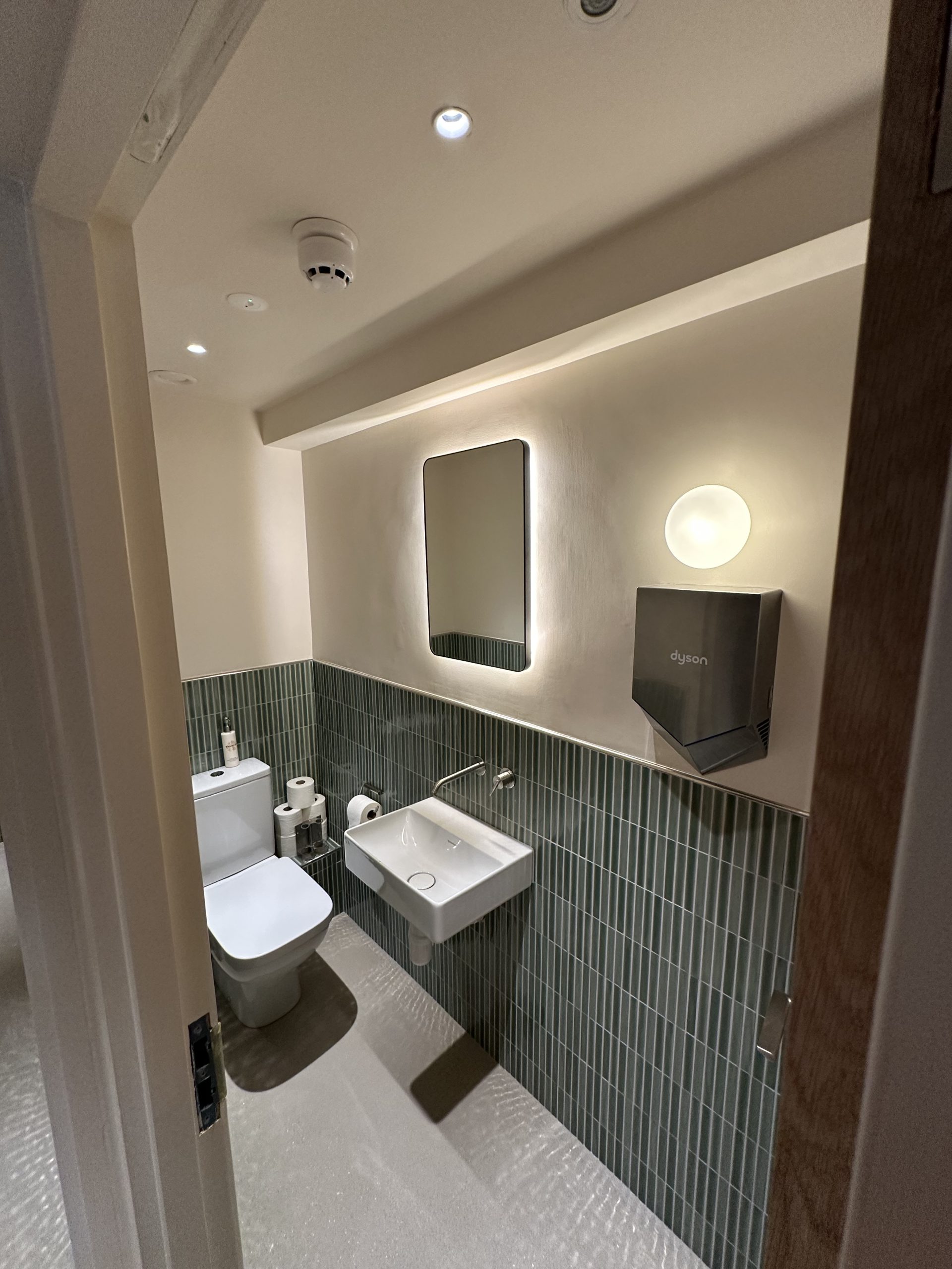 Pilates studio washroom with recessed downlights, wall light and illuminated mirror